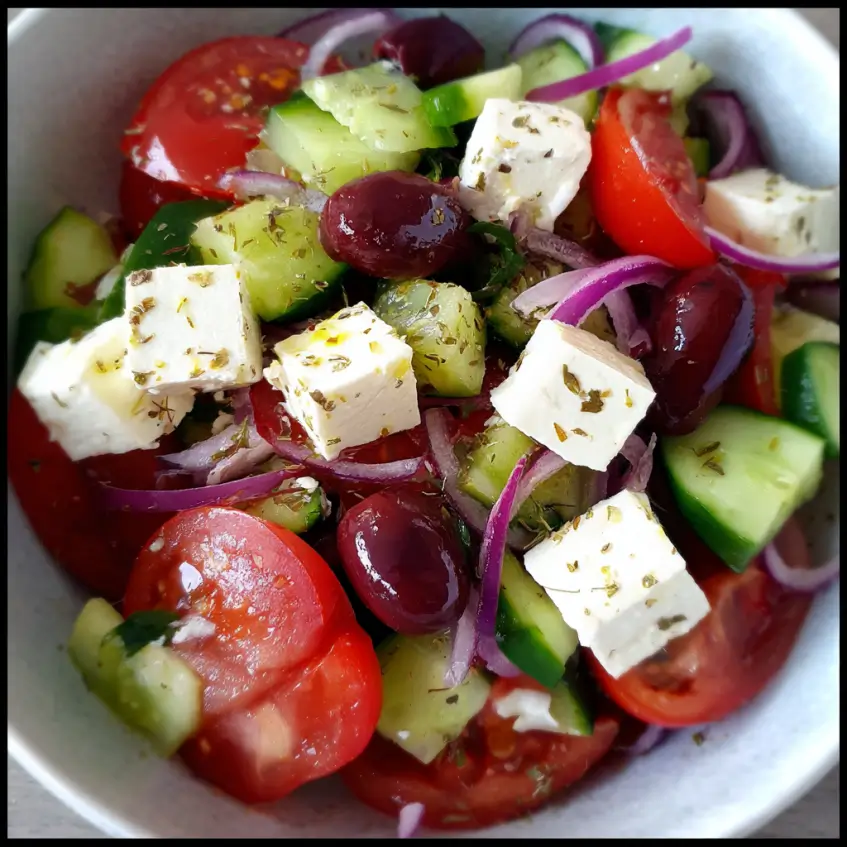 Vibrant close-up of a fresh Greek salad with ripe tomatoes, crisp cucumbers, creamy feta, and Kalamata olives.